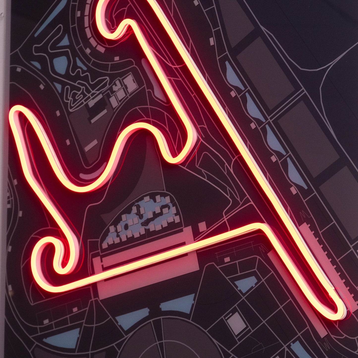 Close-up of a neon-lit race track layout on a detailed dark map backdrop