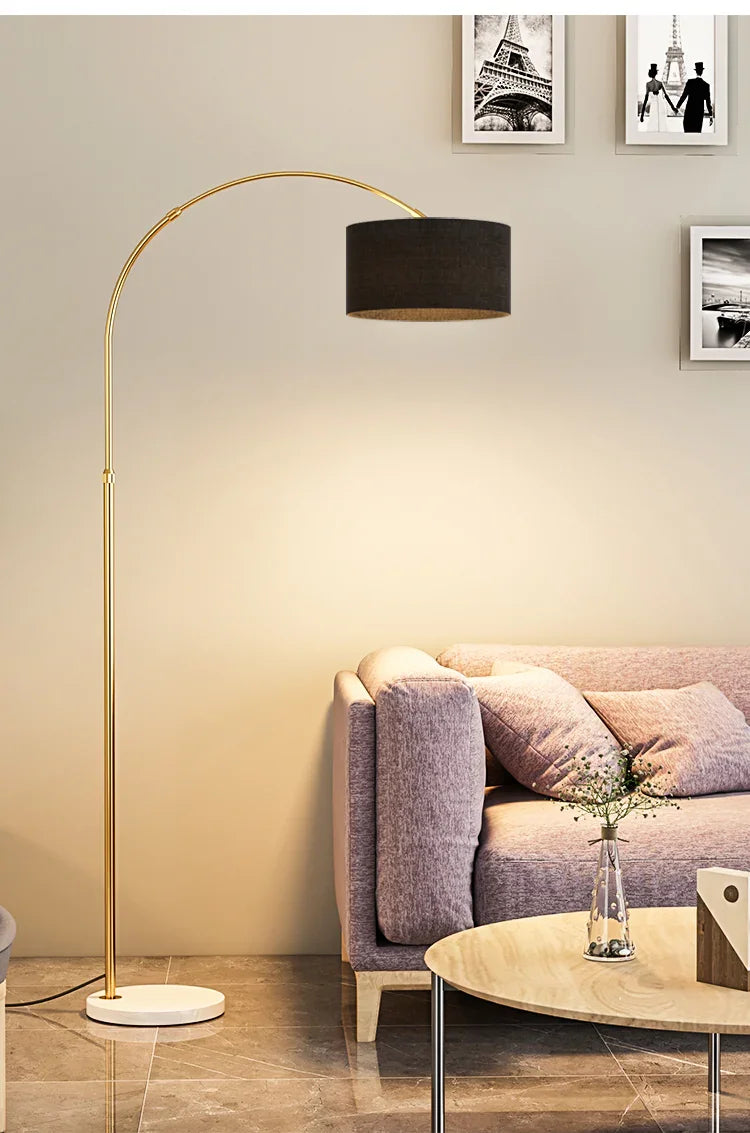 Modern living room with pink sofa, gold arc floor lamp, coffee table, and black-and-white Paris photos