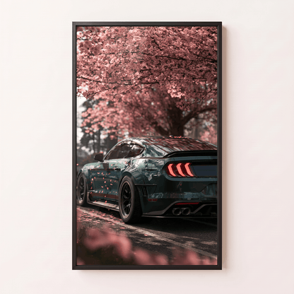 Framed canvas wall art featuring a dark muscle car parked under blooming pink cherry blossom trees in a modern black frame.