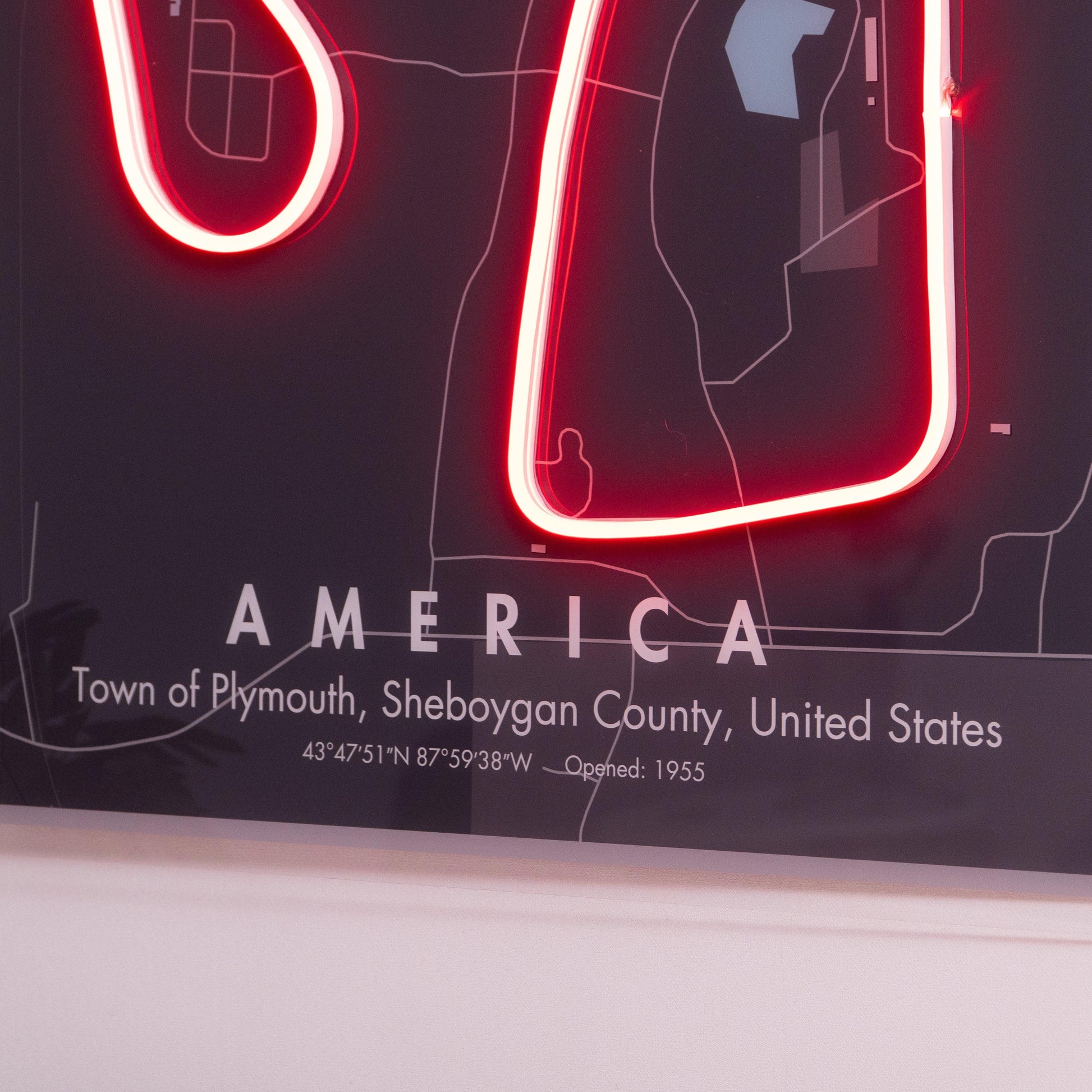 Close-up of neon sign map highlighting Town of Plymouth, Sheboygan County, USA with coordinates and open year 1955