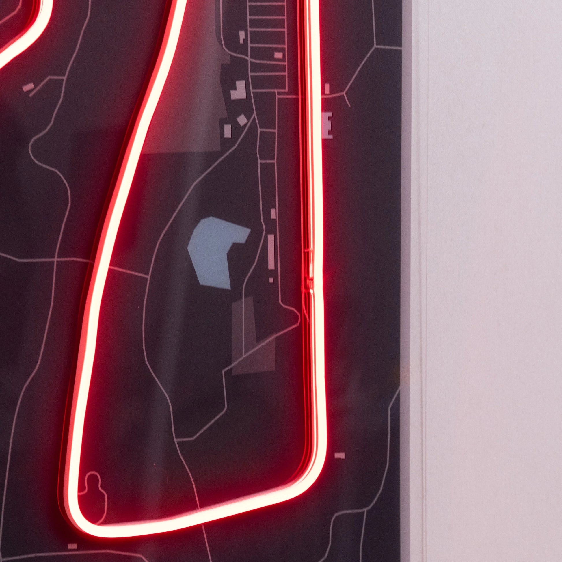 Black map wall art with red neon light outlining a track or route detail