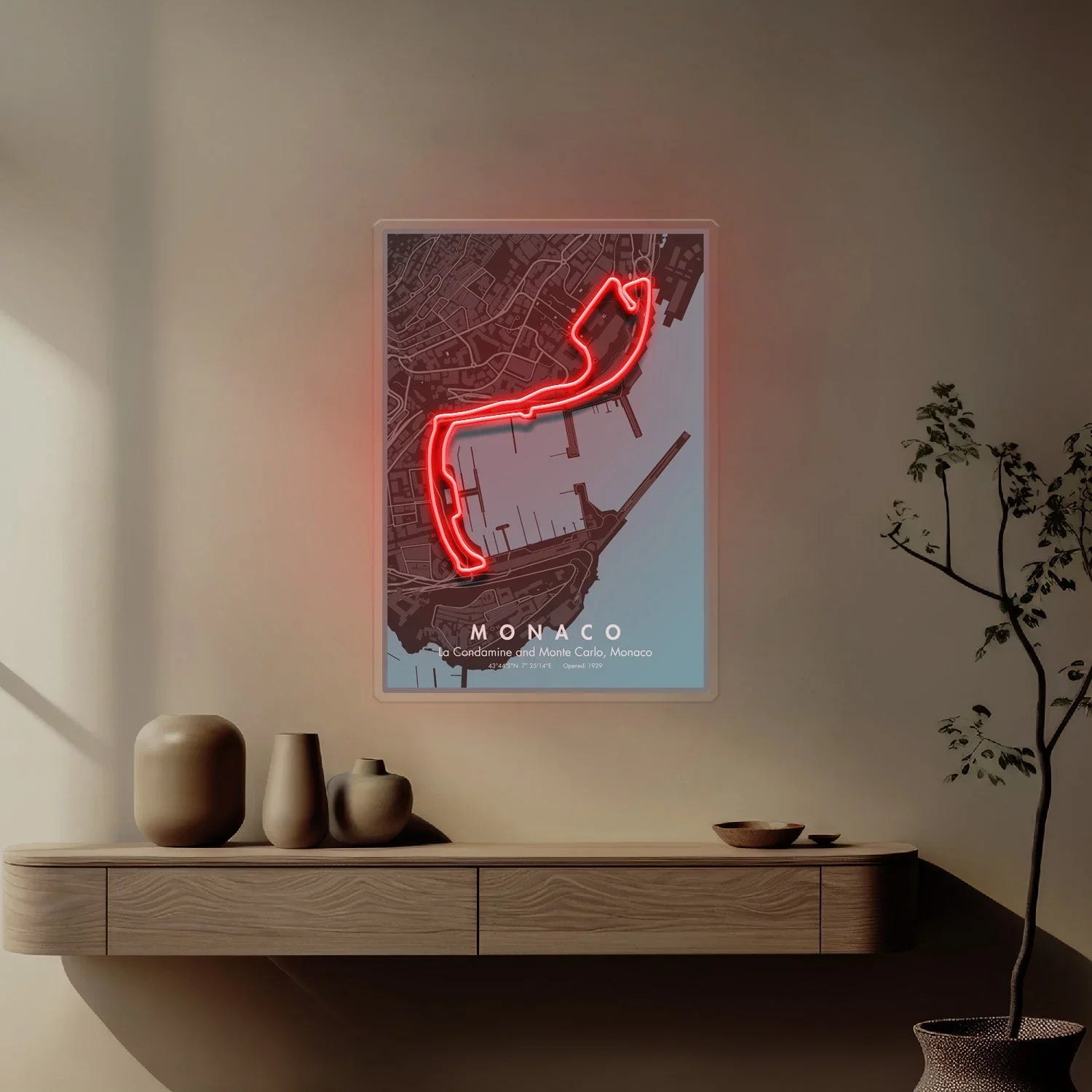 Wall art with illuminated red neon Monaco Formula 1 circuit map above wooden shelf with vases
