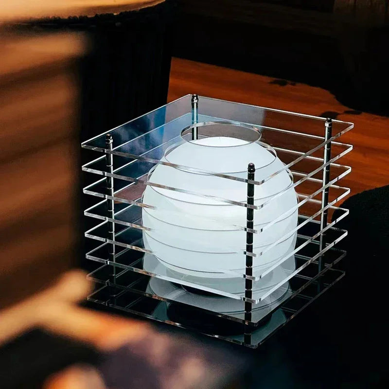 Modern decorative white spherical lamp encased in a transparent acrylic cage on dark surface